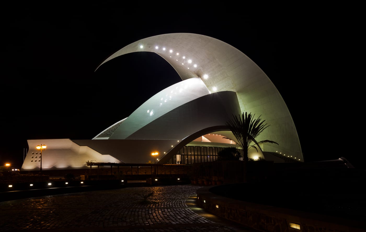 Vista nocturna del Auditorio de Tenerife iluminado, con la curva de su cubierta recortada sobre el cielo.