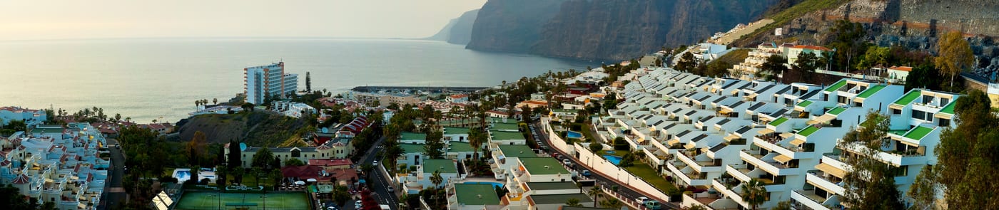 Panorámica de los Acantilados de Los Gigantes con un barco navegando junto a las paredes de roca.