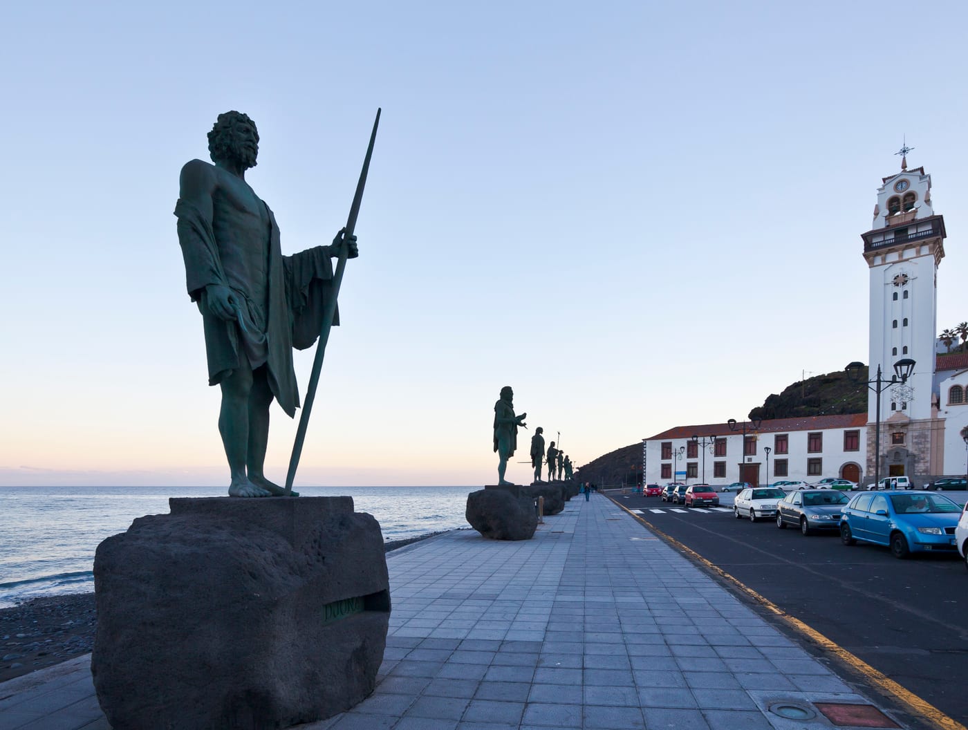 Estatua de un mencey guanche con la Basílica de Nuestra Señora de la Candelaria al fondo, Tenerife.