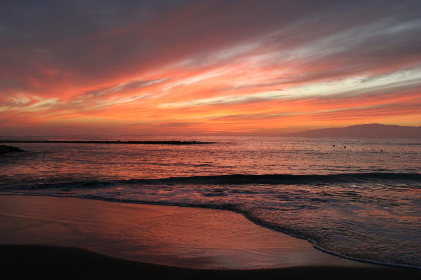 Atardecer sobre la Playa de Fañabé, con la silueta de La Gomera recortada en el horizonte.