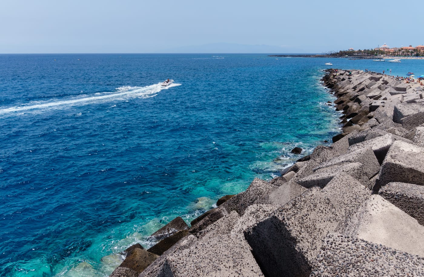 Espigón rompeolas de Los Cristianos fotografiado desde el muro del puerto, con la playa y el pueblo al fondo (Arona, Tenerife).