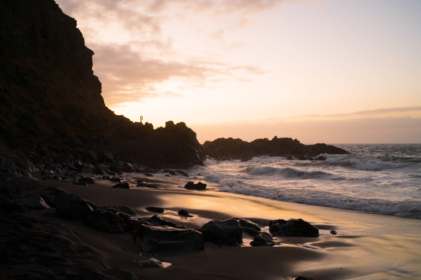 Atardecer sobre la Playa del Bollullo, con el Atlántico rompiendo sobre la arena volcánica negra.