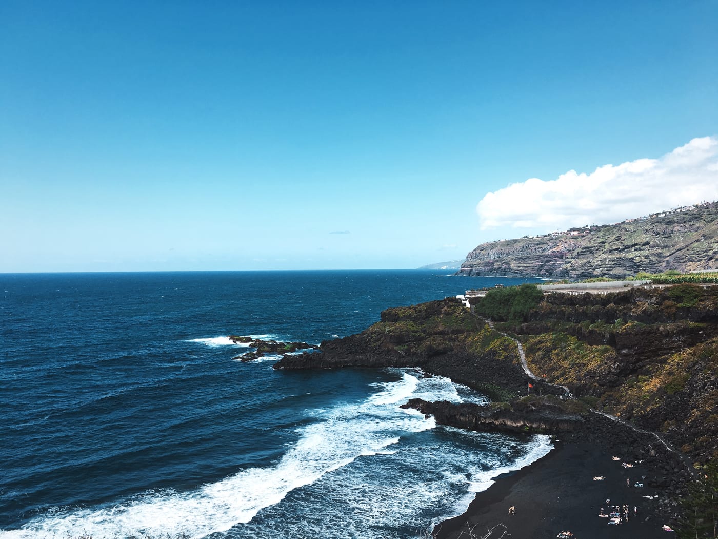 Vista panorámica de la Playa del Bollullo bajo los acantilados verdes de plataneras de La Orotava, Tenerife.