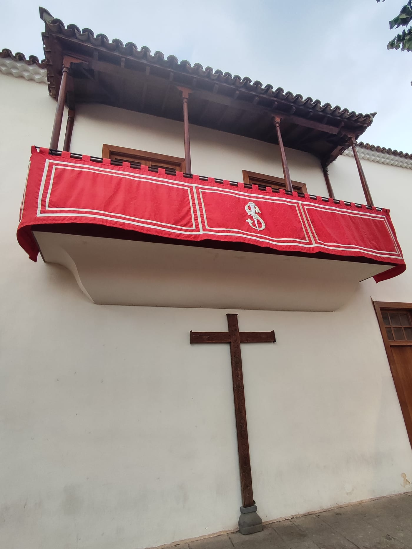Detalle del balcón franciscano con estandarte y cruz de madera en el muro del santuario