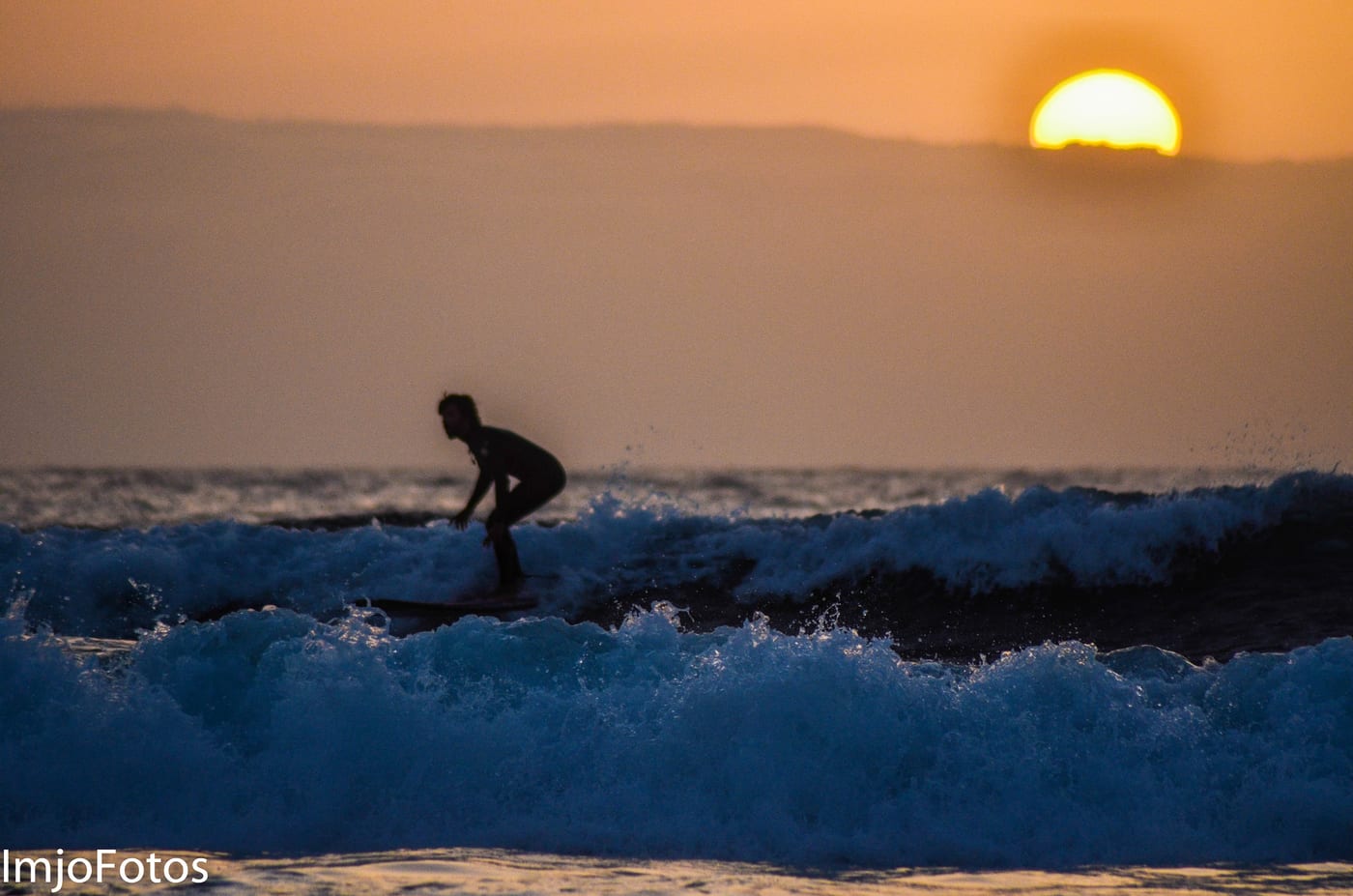 Surfista cogiendo una ola al atardecer en la costa sur de Tenerife.